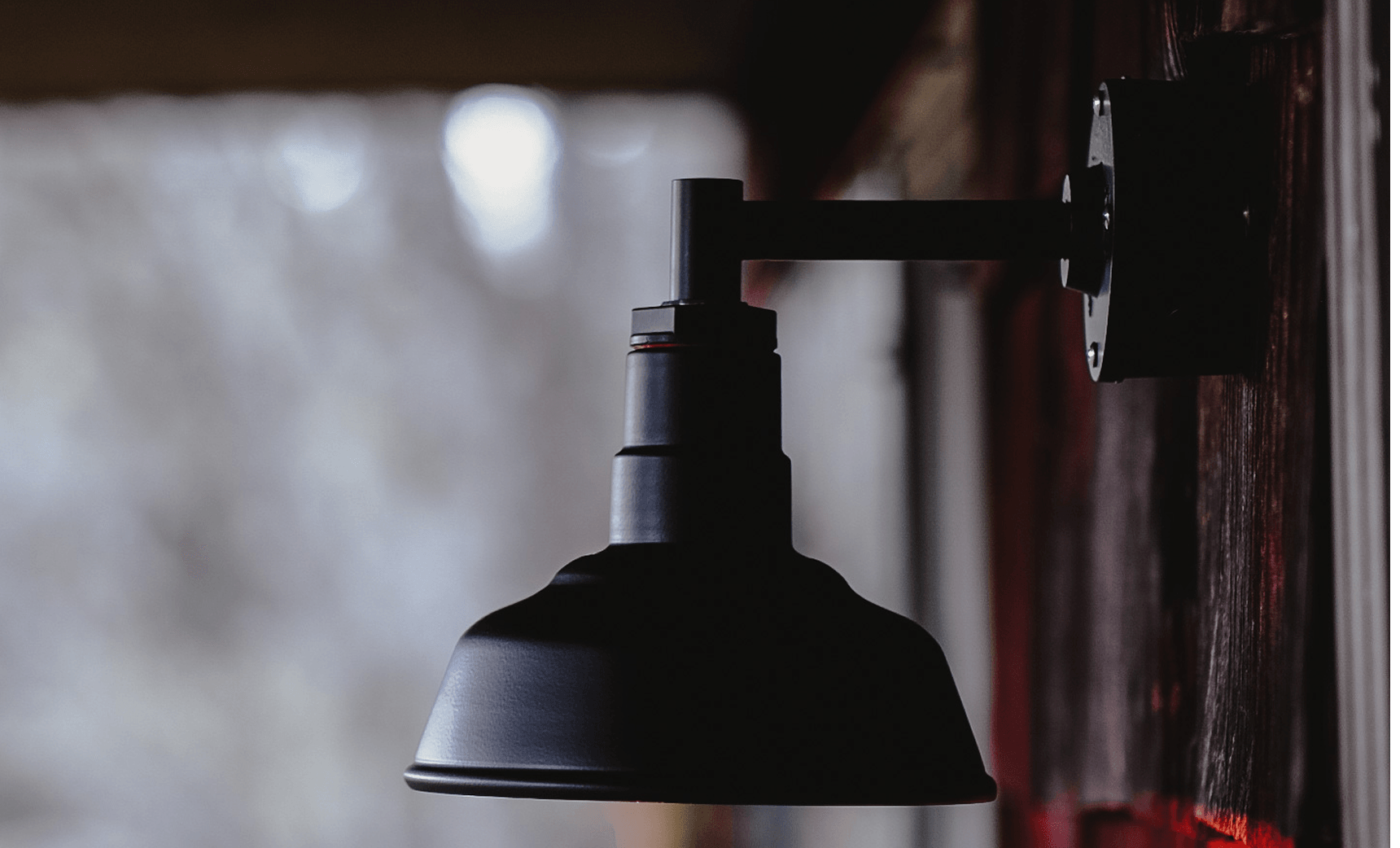 Powder-coated barn-style wall light on a cabin exterior