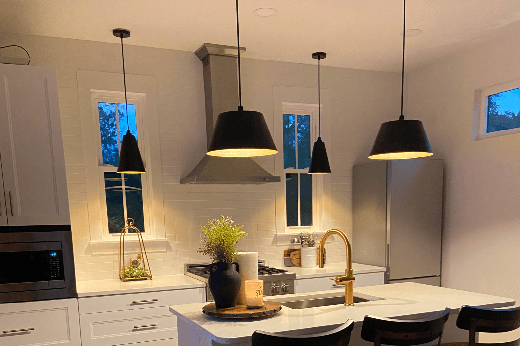 Modern kitchen with pendant lighting over island and sink, featuring warm ambiance and sleek design elements.