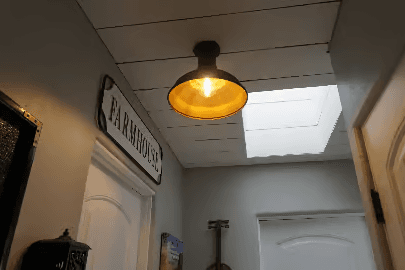 Warm light fixture in farmhouse hallway with a ceiling skylight.