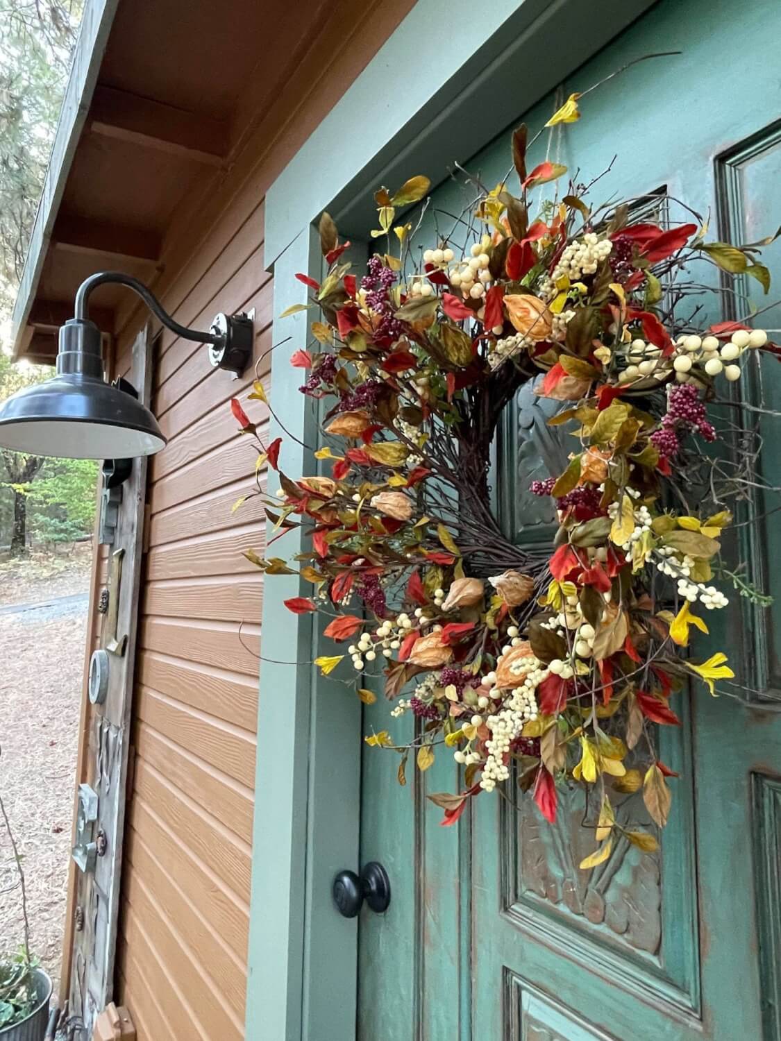 Small Barn Sconce Next to Fall Decoration on Exterior of Chicken Coop
