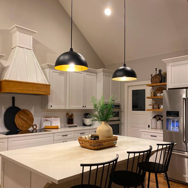 Modern kitchen with pendant lights over island, featuring white cabinets and a sleek design.