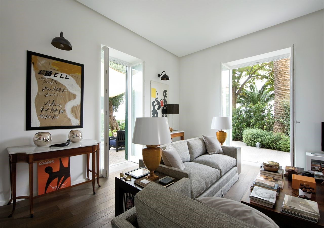 Modern living room with gooseneck wall lights, large windows, and stylish furniture.